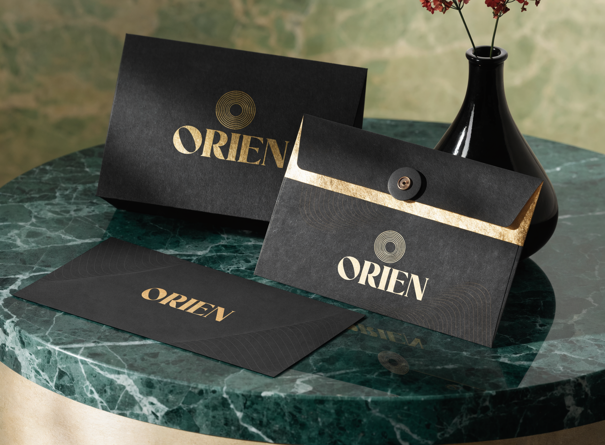 A minimal brand identity mockup on a marble surface, matte black business card with gold foil logo, matching envelope and letterhead, soft directional studio light, shallow depth of field, clean luxury aesthetic